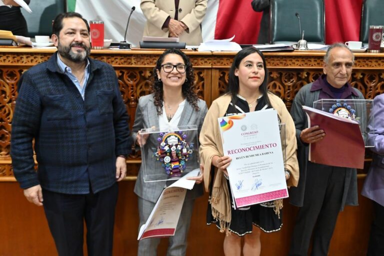 El activista Ricardo Coyotzin Torres, representante de Fuera del Clóset A.C., muestra la presea recibida en la categoría Protección a los derechos humanos, acompañado por integrantes de la comunidad LGBTTTIQNB+.