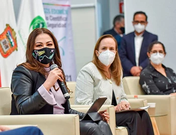 NECESARIO COMBATIR VULNERACIONES AL DERECHO HUMANO A LA SEGURIDAD CIUDADANA: CODHEM. Imagen de un foro institucional con personas sentadas en un panel, una de ellas con micrófono, durante un evento sobre seguridad y derechos humanos.