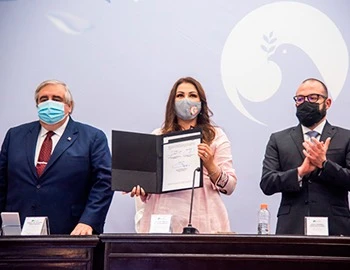 Imagen institucional de una sesión formal con tres personas detrás de una mesa; una persona sostiene un documento. La imagen se utiliza para comunicar que la CODHEM llama a actores e instancias a plantear bases para debatir sobre la despenalización del aborto.