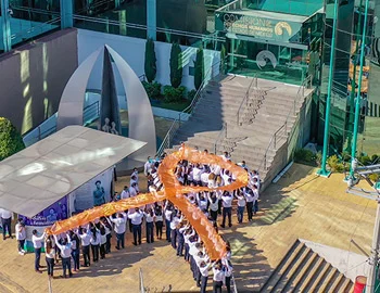 Personas formando un lazo naranja en un espacio institucional, como parte de una acción de la CODHEM para promover acciones afirmativas y educación para erradicar la violencia contra las mujeres.