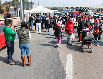 Personal de la CODHEM brinda acompañamiento y orientación a una caravana de personas migrantes que transita por el Estado de México, en un espacio público con módulos de atención.