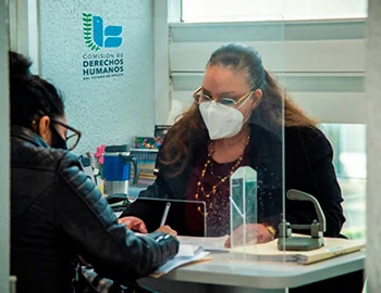 Persona de la CODHEM brinda atención gratuita a una usuaria en un módulo institucional, como parte de los servicios que el organismo mantiene disponibles durante el periodo vacacional. Línea telefónica gratuita 800 999 4000 y la página web www.codhem.org.mx