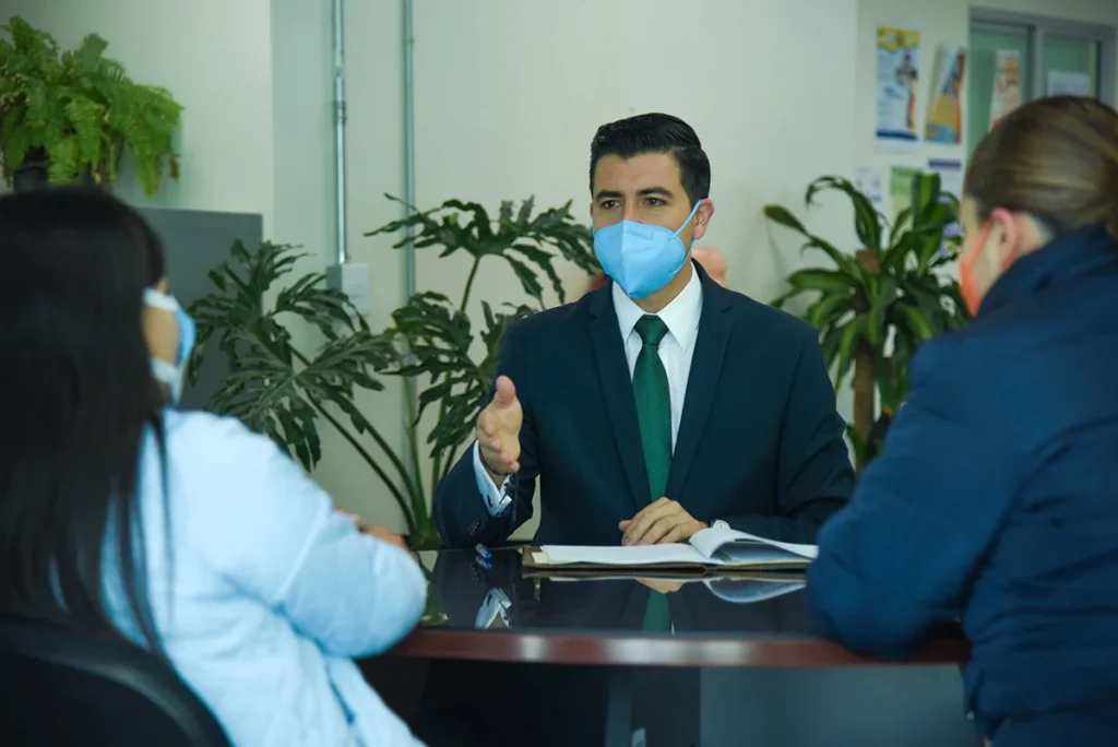 Persona de la CODHEM realiza una sesión de mediación con dos personas en una oficina, promoviendo la solución de conflictos de forma ágil y efectiva mediante el diálogo.