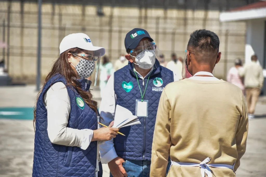 Personal de la Comisión de Derechos Humanos del Estado de México conversa con una persona en un espacio abierto, durante labores de supervisión y atención.