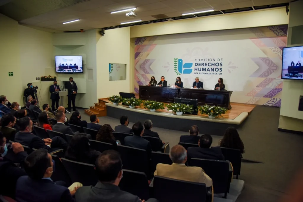 Auditorio con personas sentadas observa una mesa de trabajo institucional. En 2021, la Codhem capacitó y sensibilizó a más de 89 mil personas servidoras públicas municipales, estatales y federales
