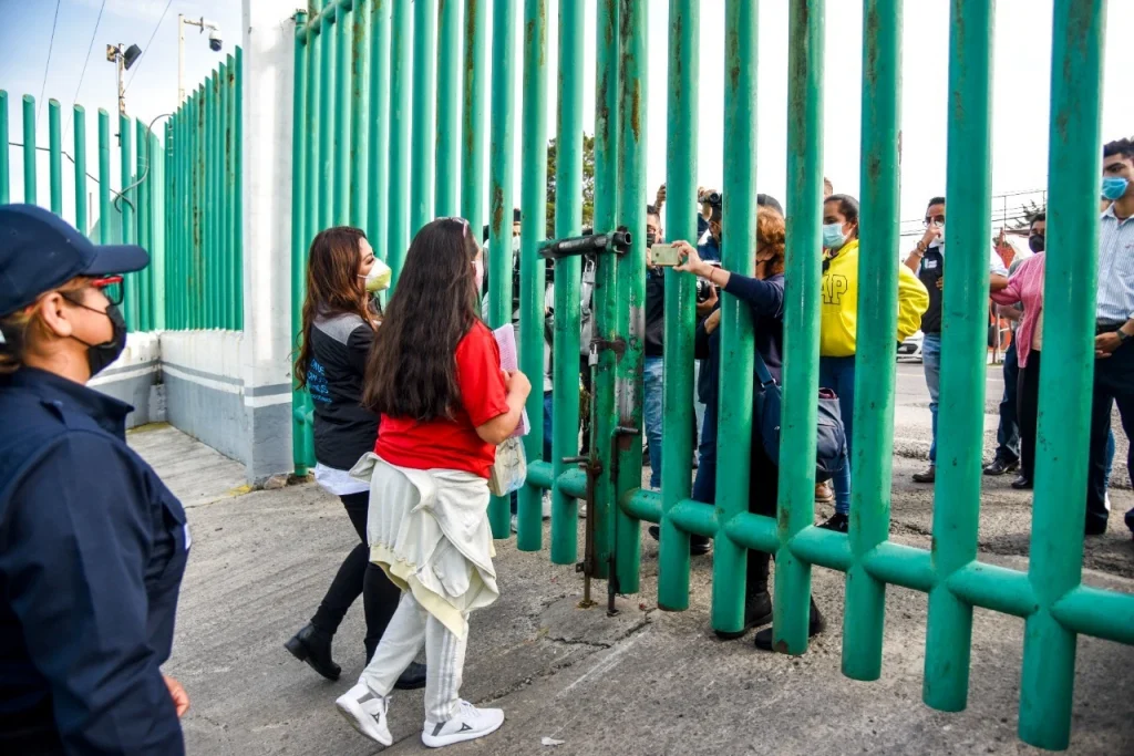 Personas reunidas frente a una reja metálica verde mientras se documenta el momento. Texto: “CONSIGUE ALEJANDRA SU LIBERTAD POR PRONUNCIAMIENTO DE AMNISTÍA DE LA CODHEM”.