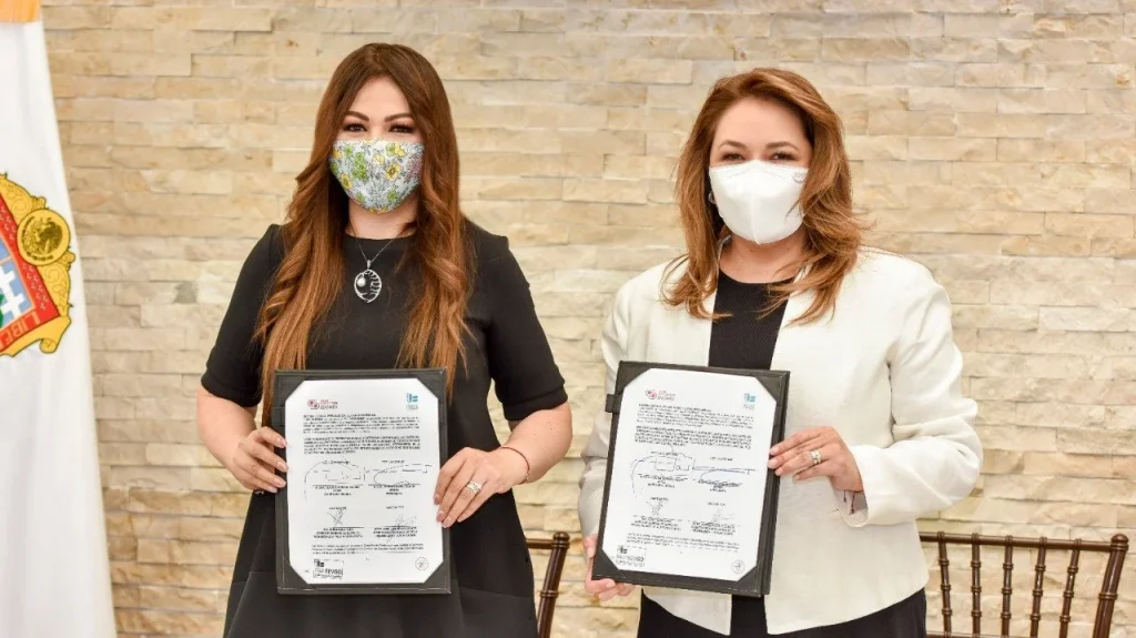 Dos personas sostienen documentos firmados frente a un fondo institucional, durante un acto de colaboración entre la CODHEM y el Secretariado Ejecutivo del Sistema Anticorrupción Estatal.