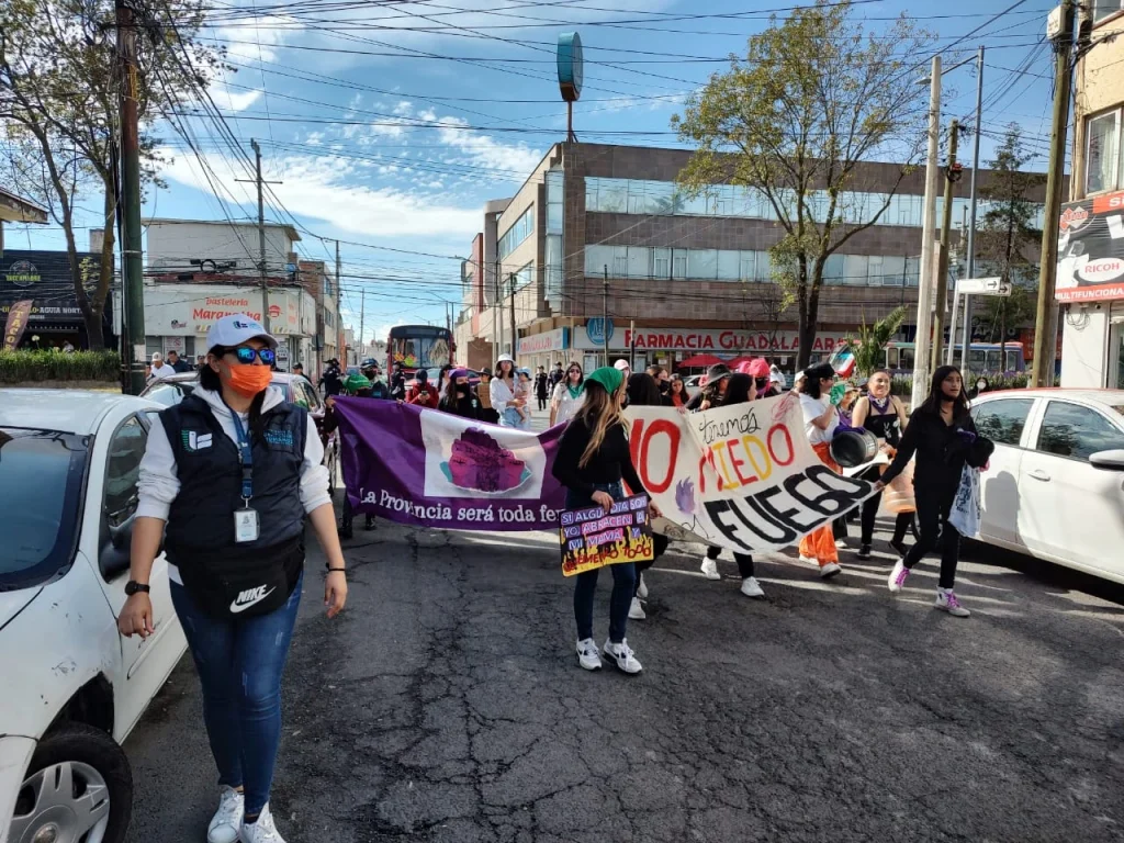 La Comisión de Derechos Humanos del Estado de México (CODHEM) desplegó personal para garantizar derechos y libertades durante una marcha del Día Internacional de la Erradicación de la Violencia contra las Mujeres, donde personas avanzan por una calle con pancartas.
