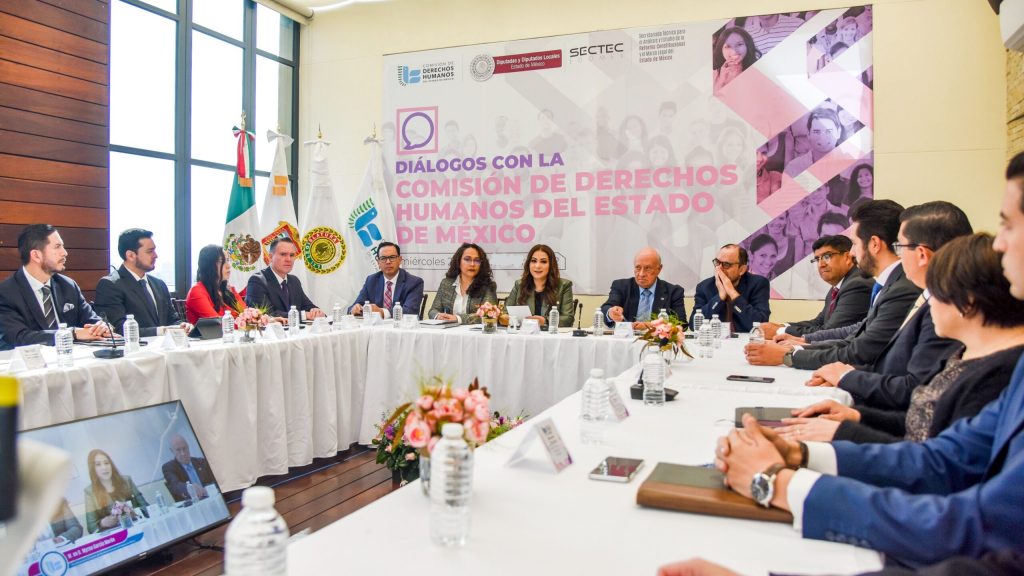 Reunión institucional en mesa redonda con participantes y banderas oficiales de fondo; se presentaron propuestas para el proyecto de reforma constitucional en un diálogo encabezado por Myrna Araceli García Morón y Mauricio Valdés Rodríguez.