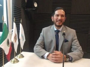 Persona en oficina sentada frente a una computadora que muestra gráficas, en un espacio institucional con teléfono y equipo de trabajo; representa el área de primer contacto de la CODHEM, donde personal brinda atención, orientación y recibe quejas de la ciudadanía.