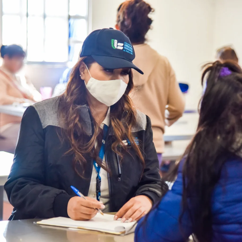 Persona con gorra de la CODHEM y cubrebocas registra información durante supervisión de actividades en el CPRS de Santiaguito en jornada electoral.