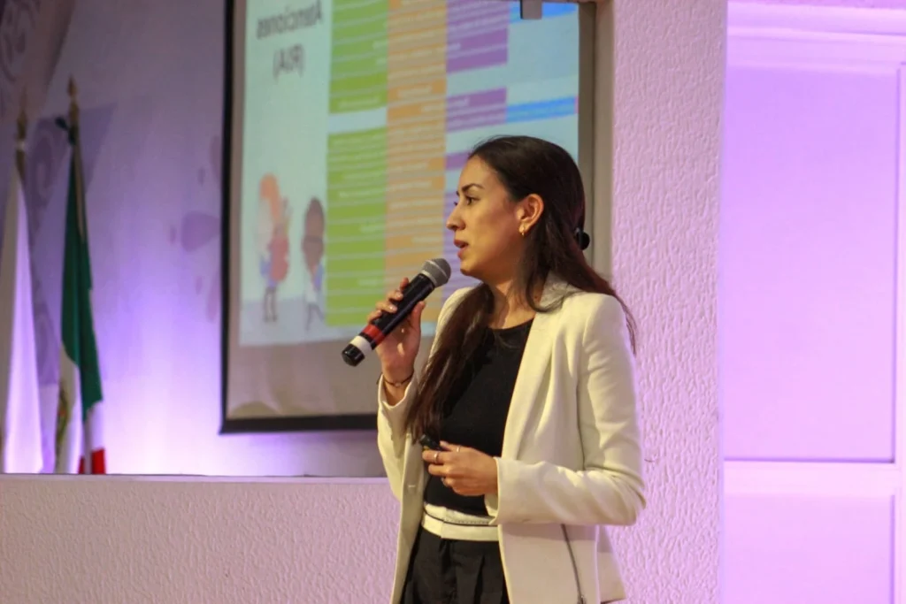 Persona ponente de la CODHEM expone con micrófono frente a presentación, destacando la necesidad de armonizar leyes y fortalecer la protección de derechos de niñas, niños y adolescentes.