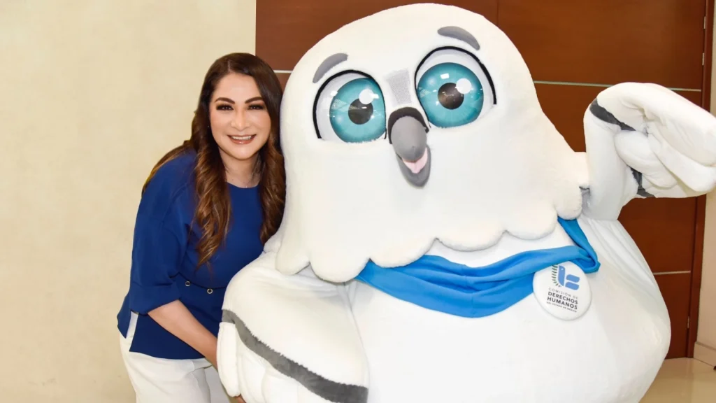 La presidenta de la CODHEM, posa junto a la nueva mascota institucional durante actividad de difusión, invitando a la ciudadanía a proponer un nombre.