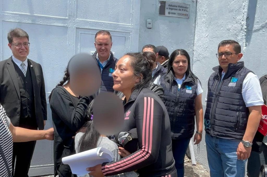 Grupo de personas reunidas frente a un edificio mientras una persona sostiene documentos y dialoga con otras, en el contexto de la novena amnistía gestionada por la CODHEM para María de la Luz “N”.