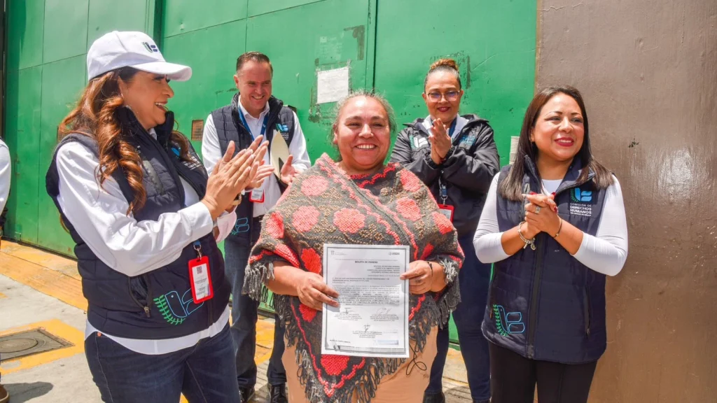 Persona sostiene un documento de amnistía mientras personal de la CODHEM la acompaña durante su entrega, en el marco de una resolución solicitada ante el Poder Judicial del Estado de México.