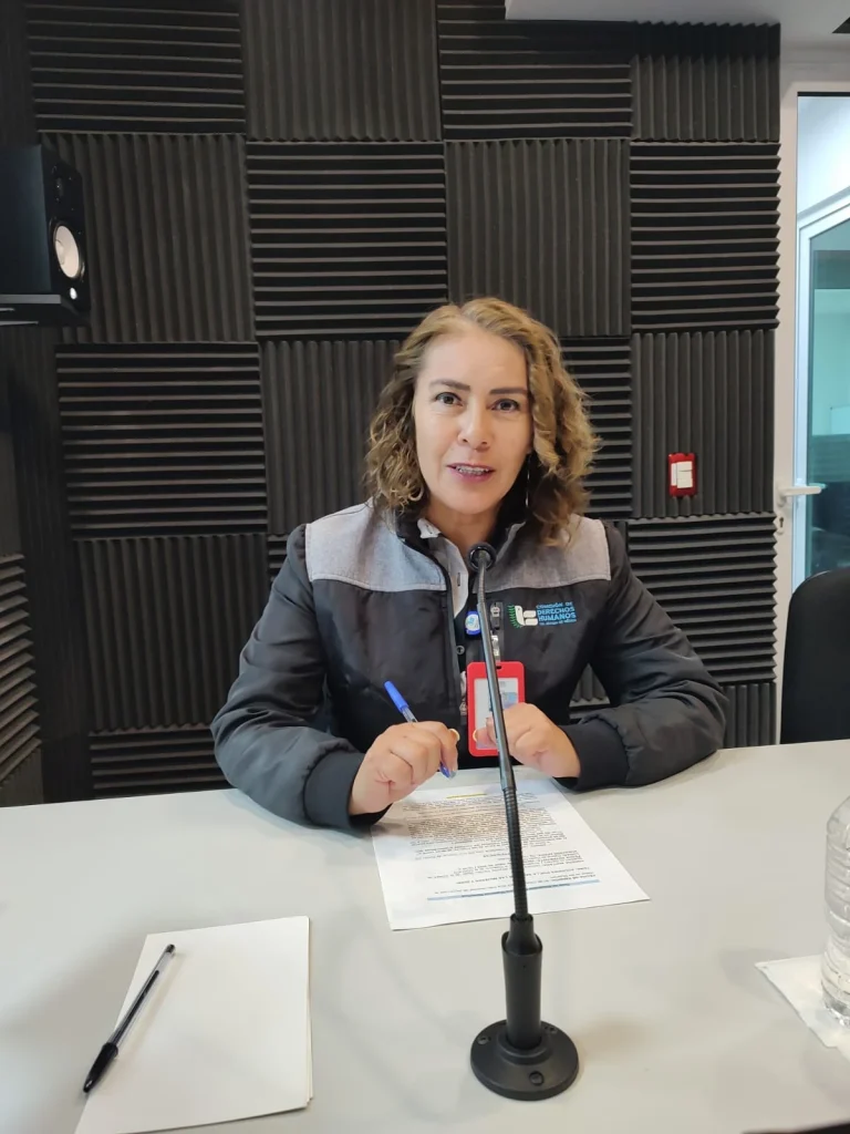 Persona de la CODHEM participa en una grabación informativa con micrófono de mesa, leyendo un documento sobre educación sexual como herramienta para prevenir el abuso sexual infantil.