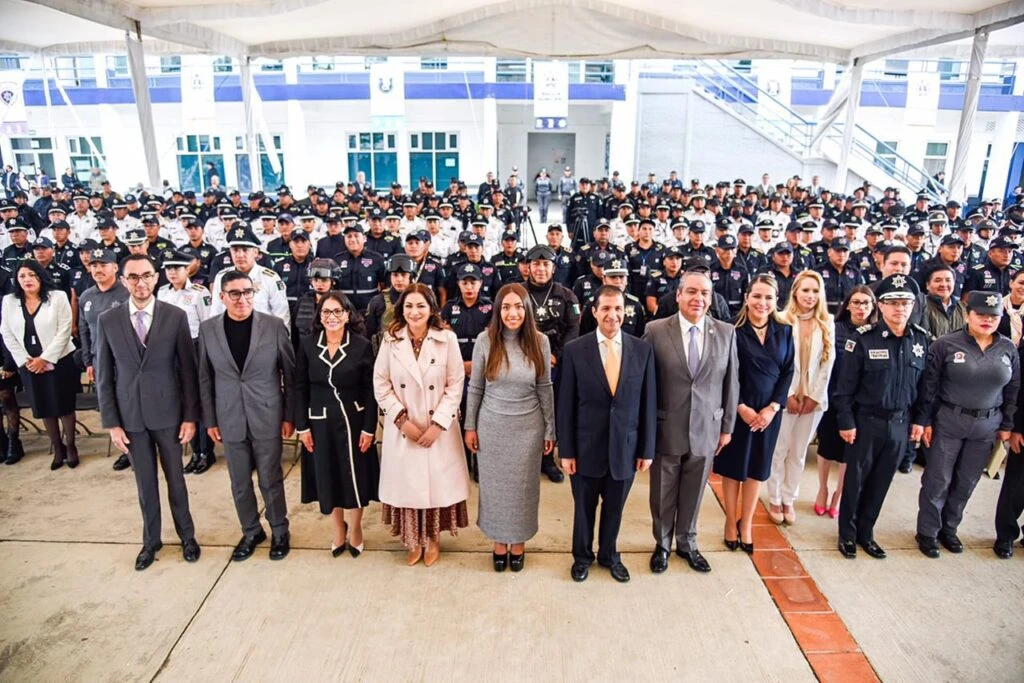 Fotografía grupal masiva en un espacio cubierto donde numerosas personas uniformadas se encuentran formadas en filas, mientras un grupo de personas al frente posa para la imagen durante un evento oficial.