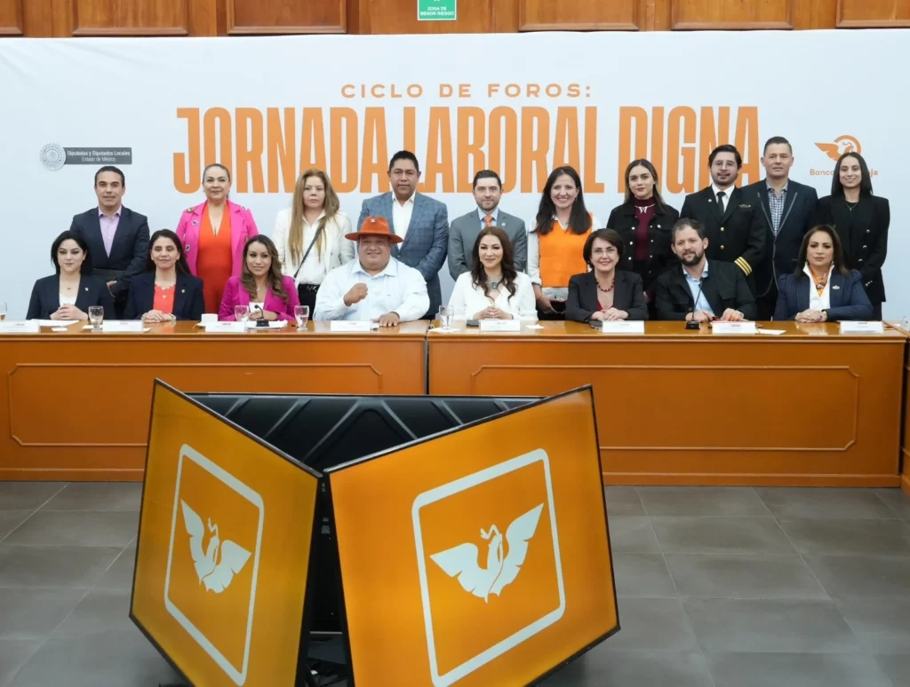 Mesa de trabajo con tres personas en un foro institucional, sentadas frente a micrófonos y documentos, con fondo que incluye el texto “Jornada Laboral Digna”.