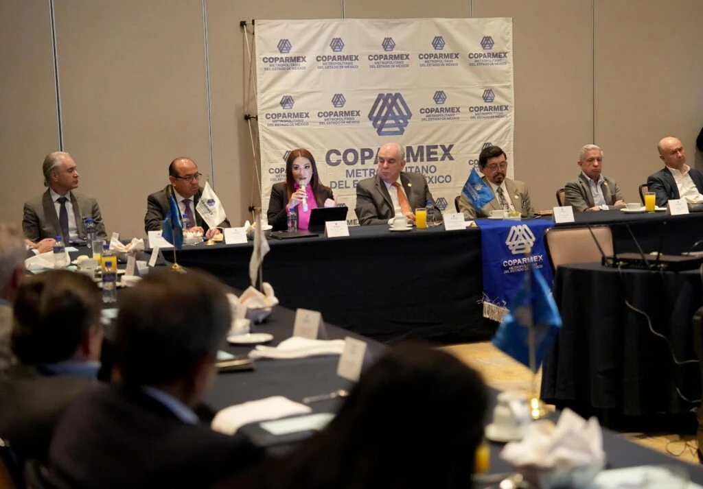 Panel de personas en una mesa principal durante una sesión de trabajo o conferencia, frente a un fondo con el logotipo de COPARMEX y asistentes en primer plano.