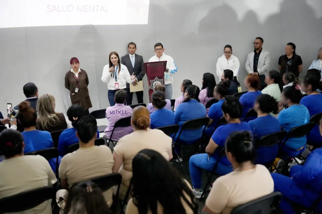 Evento sobre salud mental donde varias personas exponen frente a una audiencia sentada, en un auditorio con presentación proyectada y logotipo institucional visible.