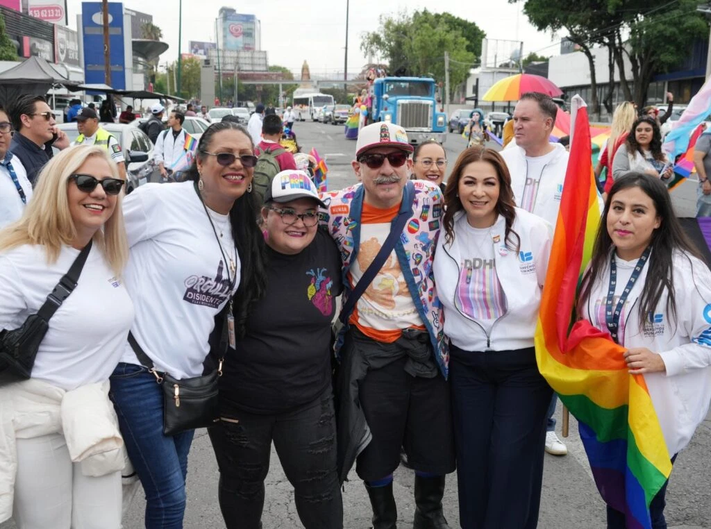 Encuentro de atención ciudadana en un recinto oficial. Dos personas dialogan y estrechan las manos mientras otras personas observan alrededor, en un espacio acondicionado para actividades de atención y participación social.