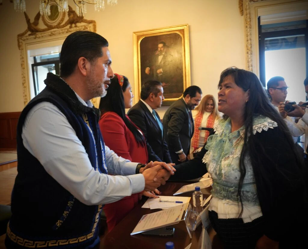 Representantes institucionales saludan a una persona integrante de una comunidad indígena durante un acto relacionado con la resolución de amnistía otorgada a Tomás “N”, resultado del pronunciamiento promovido por la Comisión de Derechos Humanos del Estado de México.