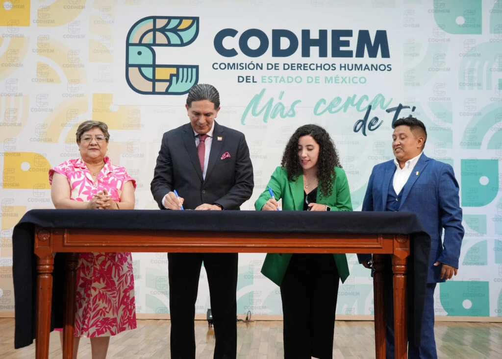 El presidente de la Comisión de Derechos Humanos del Estado de México (CODHEM), Víctor Leopoldo Delgado Pérez, firma un convenio junto con personas activistas y defensoras de derechos humanos frente al mural institucional de la CODHEM. La imagen corresponde a la formalización de instrumentos de buena voluntad concebidos como herramientas de colaboración para fortalecer la promoción y protección de los derechos humanos.