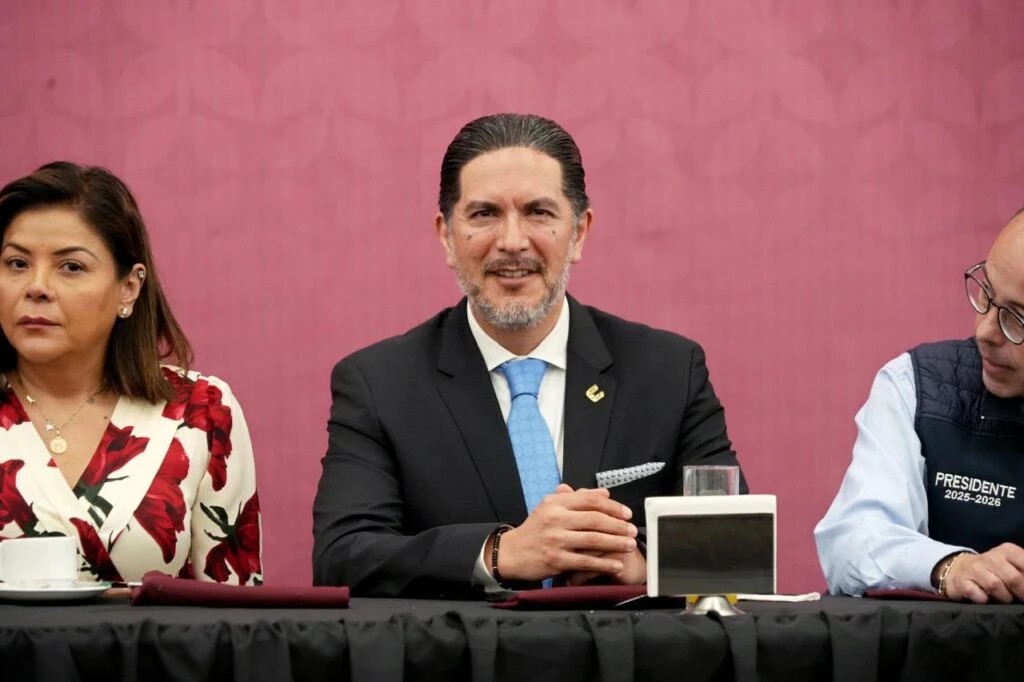 Escuchar a las personas, acercarles los servicios y prevenir vulneraciones a sus derechos han sido prioridades del primer año de Víctor Leopoldo Delgado Pérez al frente de la Comisión de Derechos Humanos del Estado de México interactúa en un espacio público arbolado, mientras otras personas permanecen al fondo de la escena. La imagen muestra un encuentro comunitario al aire libre.